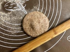 把圆面团按扁，擀成中间厚四周薄的圆片