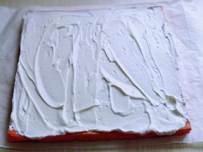 将蛋糕片放一张油纸上面，打发的奶油涂抹在蛋糕片上。借助擀面杖和油纸从一段卷起来即可，放入冰箱冷藏1小时以上再切开。(奶油留一些，做装饰用)