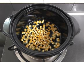 把控干水分的玉米粒放入砂锅中，用勺子拌匀，让每粒玉米都沾上黄油。