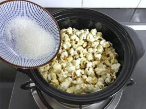 等听到锅中的噼啪声变小时，打开盖子，把白砂糖放入锅中，拌匀。