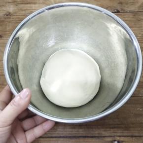 手沾黄油，面团整圆，放入发酵盆里