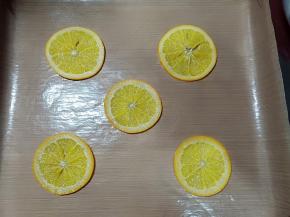 煮好的橙子晾凉后用厨房纸吸干水分，摆入烤盘