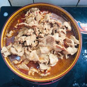 把煮好的肉片倒进碗里的配菜上。