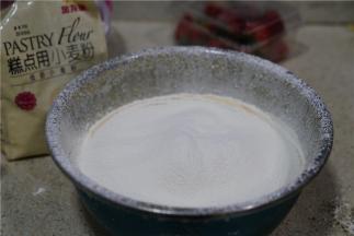 然后将金龙鱼糕点用小麦粉过筛加至蛋黄里面，因为用到的面粉量微多，所以过筛一下有助于拌制。