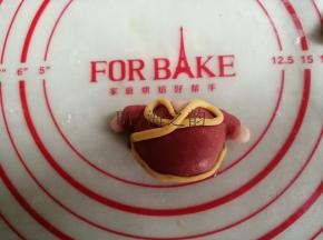 黄色面团搓成细长条，如图摆放，用水粘牢，做成过年唐装样式