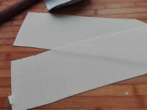 将醒发好的面团取出放在案板上，用擀面杖将其擀成薄片，越薄越好，将其切成整齐的长方形。