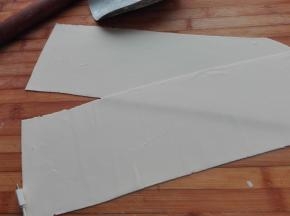 将醒发好的面团取出放在案板上，用擀面杖将其擀成薄片，越薄越好，将其切成整齐的长方形。