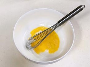 往猪油内加入鸡蛋液，用手动打蛋器稍微拌拌。