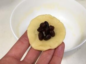 把小圆团按扁，包入2克的蜜红豆。