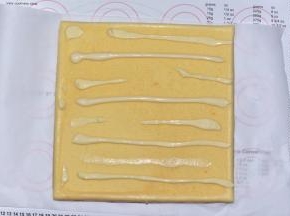 将放到手背温度的蛋糕卷移到油纸上，毛巾面刷上沙拉酱
