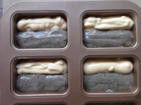 将两种不同颜色的蛋糕糊分别放入两个裱花袋里，剪个小口，同时将蛋糕糊挤入模具内，不一定要这种模具，可以用其他纸杯蛋糕模具也行。如果是用这种模具需要提前在模具内刷一层黄油，更易脱模