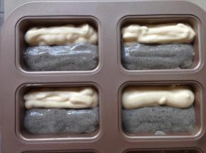 将两种不同颜色的蛋糕糊分别放入两个裱花袋里，剪个小口，同时将蛋糕糊挤入模具内，不一定要这种模具，可以用其他纸杯蛋糕模具也行。如果是用这种模具需要提前在模具内刷一层黄油，更易脱模