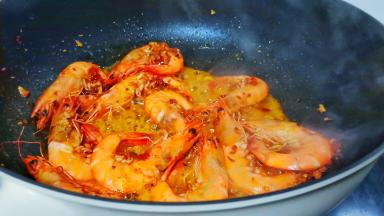 加对虾翻炒，炒至虾身卷曲变红。
