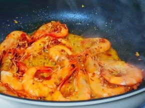 加对虾翻炒，炒至虾身卷曲变红。