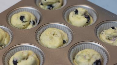 12. 将面糊装入裱花袋，裱花袋前段要剪一个比较大一些的口，不然面糊中的蓝莓会被卡住。。。卡住。。卡。。。住。。。切记 (((;꒪ꈊ꒪;)))。模具中提前铺好相应尺寸的油纸托，面糊挤至9分满