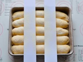 放进烤箱，30度进行二次发酵，发酵至两倍大即可，发酵好的面团，用纸剪成两个长条状，放在面团上面，筛上高筋面粉