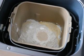 倒入芝士粉，然后在面包粉中间挖个洞，加入干酵母粉；