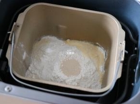 倒入芝士粉，然后在面包粉中间挖个洞，加入干酵母粉；