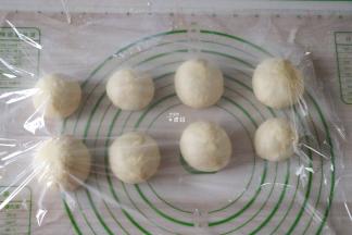 选择揉面程序揉面5分钟排气，然后分割成八等份一一揉圆，盖上保鲜膜静置松弛15分钟；