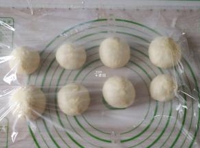 选择揉面程序揉面5分钟排气，然后分割成八等份一一揉圆，盖上保鲜膜静置松弛15分钟；