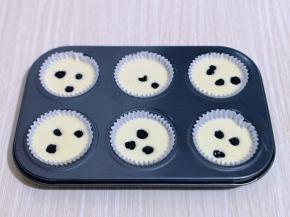 再把做好的蛋糕液倒入纸托中，每个纸托里再放上几颗蓝莓，轻轻震动模具，将气泡震出。