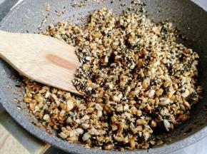 立即把花生芝麻倒入锅里，并翻拌均匀，使每一颗花生和芝麻都粘上糖浆