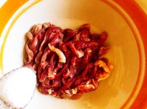 将肉切成均等的丝，加入盐。