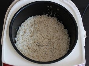 大米洗净浸泡10分钟，倒入电饭锅，加适量的水，比平时煮饭的水少一边，盖子盖子按煮饭键。大米浸泡不仅省电，米饭更加香软。
