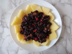 将腌制好的排骨、豆豉酱料和辣椒圈摆放到土豆块上面。