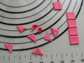 剩下的面片先切出正方形，然后斜切成三角形，窝起来做成猪的耳朵。一共二十个小耳朵。