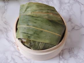 将多余的粽叶翻折过来，覆盖住糯米排骨，整个包裹起来。