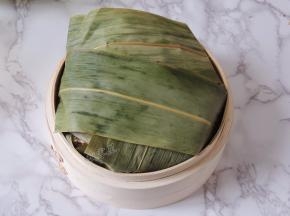 将多余的粽叶翻折过来，覆盖住糯米排骨，整个包裹起来。