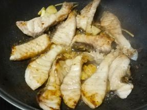 时间到开锅盖转中大火，将鱼块翻面煎至微黄