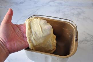 启动面包机的揉面程序，15分钟后面团表面光滑柔软，轻拉可见薄膜，这时就可以加入黄油了。