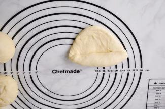 用擀杖擀成椭圆形。然后将椭圆形的面团从上到下卷起来。