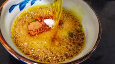 碗里放辣椒面、熟芝麻、豆鼓、盐、葱花、将一半的菜籽油分次浇在辣椒碗里，用筷子快速搅匀。