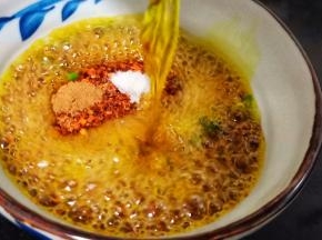 碗里放辣椒面、熟芝麻、豆鼓、盐、葱花、将一半的菜籽油分次浇在辣椒碗里，用筷子快速搅匀。
