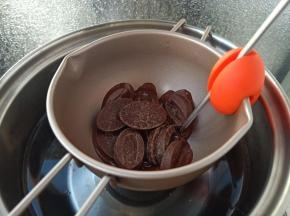 把法芙娜黑巧克力放入阳晨巧克力融化锅里。然后隔水小火加热。放一个针式温度计。
