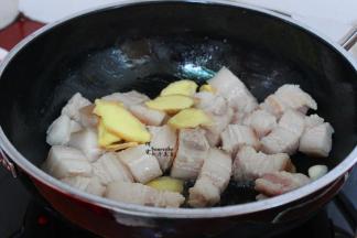 用炒锅，烧热，少许油，把汆烫好的五花肉块放入锅，加几片生姜一起翻炒至微黄，油脂出来。