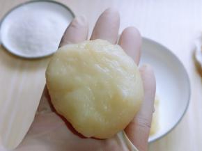 戴上食品手套，取一块糯米团，用掌心压扁，放上一块芒果，包起来，收口捏紧。