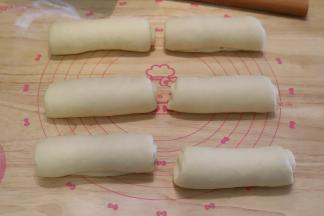 依次将面团分别擀成牛舌状，从上往下卷好，盖保鲜膜松弛20分钟。