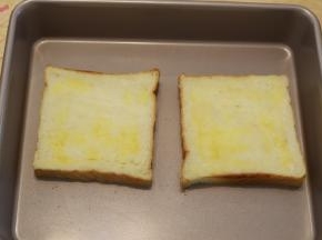 放入烤盘，黄油融化后刷在吐司片上。