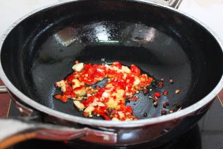 把炸过鱼的油装好，锅中留少许油，放入洗净切好的大蒜、红辣椒、生姜，小火煸炒出香味，