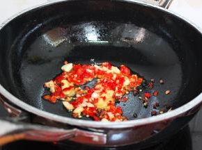 把炸过鱼的油装好，锅中留少许油，放入洗净切好的大蒜、红辣椒、生姜，小火煸炒出香味，