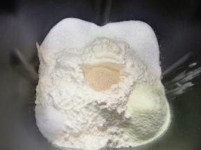 依次加入高筋面粉和奶粉，糖和盐对角放，面粉中间挖个洞放入干酵母盖起来，启动面包机的“自动和面”程序15分钟。