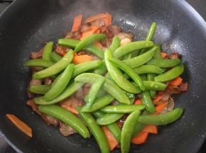 接着倒入荷兰豆，继续翻炒均匀