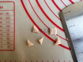 将粉色面团揪出一点，擀成面片，切成正方形，再对角切，共切出10个三角形，用来做5只小猪的耳朵