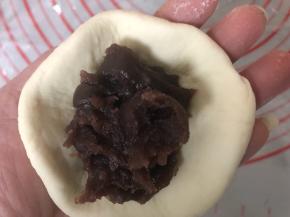 取一个小剂子擀开，包入适量豆沙。