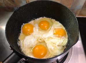 把锅烧热然后注入食用油，鸡蛋我没有打散，因为这样子炒出来的颜色比较丰富多彩，如果你喜欢把鸡蛋打散也是可以的，磕入鸡蛋先别急着去炒它，让先它煎一下