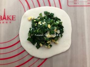 取一个小剂子擀成大圆饼皮，码上韭菜鸡蛋馅